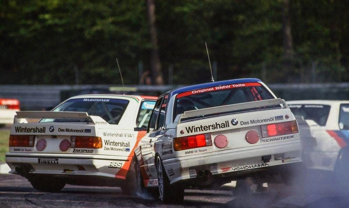 Two bmw e30 m3 racing cars on a track with visible branding.